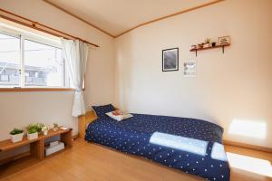 東京にあるUU Houseの青いベッドと窓のある寝室