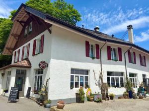 a large white building with red shuttered windows at Le Point du jour in Saint-Cergue