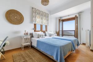 a bedroom with a blue and white bed and a balcony at Villa Margini, Aegean Views , Pool Villa, Skopelos in Skopelos Town +48 photos