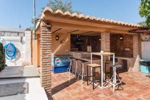 un patio con cocina y un bar con taburetes en Casa Jacamar, en Marbella