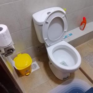 a bathroom with a white toilet with a yellow bucket at Yellow Petals Homestays in Nanyuki