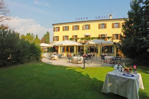 a hotel with tables and chairs in front of a building at Hotel Sirena in Lazise