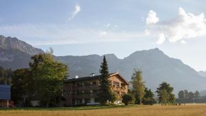 a building in a field with mountains in the background at Bauernhof Lindenhof in Scheffau am Wilden Kaiser