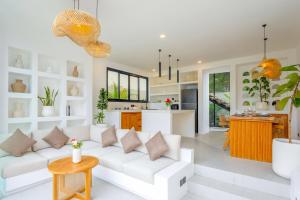 a living room with a white couch and a kitchen at Villa Kanu in Uluwatu