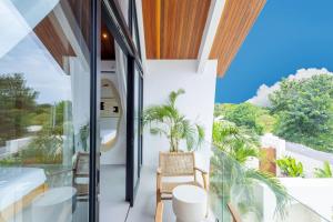 a balcony with a view of the ocean and palm trees at Villa Kanu in Uluwatu
