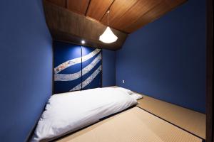 a bed in a room with a blue wall at Yuzen TABI-NE in Kanazawa