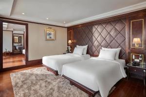 Un dormitorio con dos camas y una pared. en Verdure Lotus Classic Cruise on Lan Ha Bay, en Ha Long