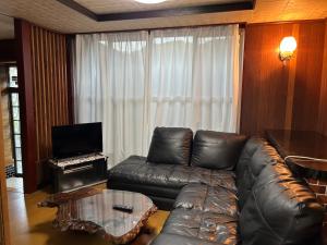 壹岐市一棟貸し民泊宿松山荘的配有皮沙发和桌子的客厅