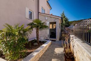 a house with a fence and trees in front of it at Apartment Bellistra Rabac in Rabac