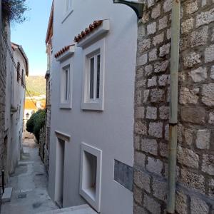 a narrow alley with a white building and a stone wall at Sveti Marin Rab in Rab