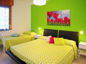 ビビオーネにあるAppartamenti Azzurroの緑の壁と赤い花が特徴の客室で、ベッド2台が備わります。