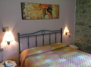 1 dormitorio con 1 cama, 2 lámparas y una pintura en Albergo Elisa en Comano
