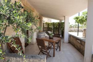 an outdoor patio with a wooden table and chairs at Antica Masseria Ficazzana - Tenuta in Marina di Pescoluse