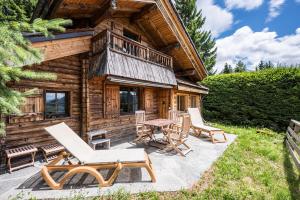 a log cabin with a patio and chairs and a table at Chalet Vardasse in Manigod