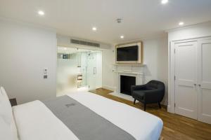 a bedroom with a bed and a chair and a television at The Z Hotel Gloucester Place in London