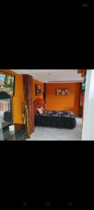 a bedroom with two beds and an orange wall at Cabañas Ángela 3 in Mazamitla