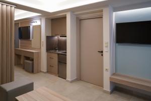 a room with a kitchen with a television and a door at Nepheli Apartments and Studios in Paralia Katerinis
