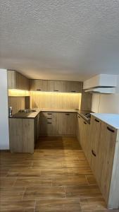 an empty kitchen with wooden cabinets and a wooden floor at Pension Tofalvi in Harghita-Băi