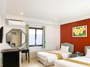 a hotel room with two beds and a mirror at The Corner in Patong Beach