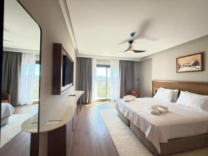 a hotel room with a bed and a television at Cunda Kızılca Deluxe Hotel & SPA in Ayvalık