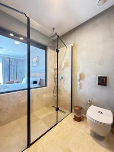 a bathroom with a shower and a toilet and a bed at Cunda Kızılca Deluxe Hotel & SPA in Ayvalık