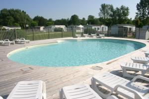 a large swimming pool with white chairs at Camping Val de Boutonne in Saint-Jean-dʼAngély