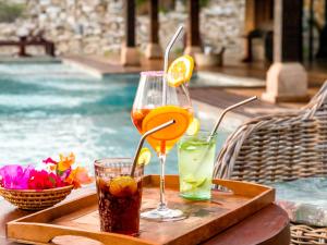 a tray with two drinks on a table next to a pool at Demeure de la Compagnie Générale des Huiles Précieuses in Fiserenamasay