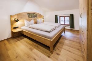 une chambre avec un grand lit avec une tête de lit en bois dans l'établissement Aschenauer Hof, à Ruhpolding