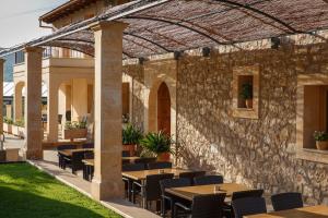 a patio with tables and chairs and a stone wall at Agroturismo S'Arboçar in Sant Llorenç des Cardassar