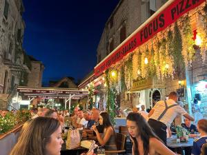 Un grupo de personas sentadas en mesas afuera de un restaurante. en Chatarina Apartment, en Trogir