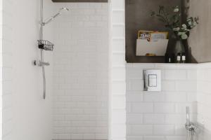 a white bathroom with a shower with a vase of flowers at Prestige Apartments 37 in Wrocław +16 photos