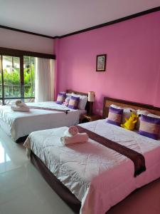 2 Betten in einem Zimmer mit rosa Wänden in der Unterkunft Grand Thai House Resort in Lamai