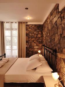 a bedroom with a bed with a stone wall at Vila 650 sqm, with Private Pool, 10 bedrooms with ensuite bathrooms & kitchen to each room - Elia Village by Irida Iris Group in Plomarion