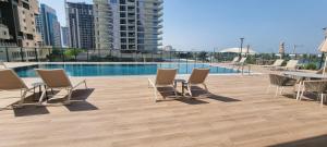a patio with chairs and a table and a pool at Skyline Luxe Sea view Apartemnt in Lusail