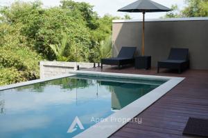 una piscina con dos sillas y una sombrilla en Riverside Villa - Nyanyi Beach, en Cemagi