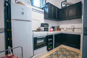 a kitchen with black cabinets and a white refrigerator at Dar Rania in Tangier