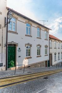 a white building with a green door on a street at Celtic Lodge - Guest House in Viseu