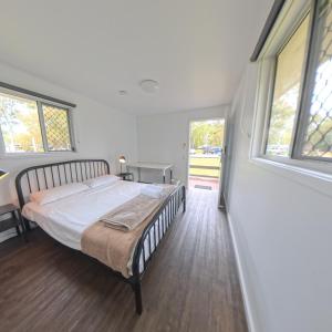 a bedroom with a bed and two windows at Kangarooms Noosa Everglades in Cootharaba