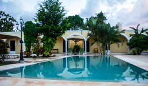 a swimming pool in front of a building with trees at Hotel Hacienda Izamal in Izamal