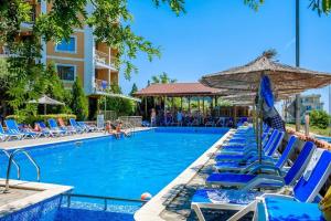 a swimming pool with blue chairs and an umbrella at Vemara Club Villas in Byala