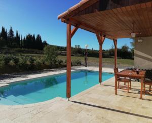 a pavilion with a picnic table and a pool at Villa Chez Nous, 8 Pers, Domaine De Ribiere in Grospierres