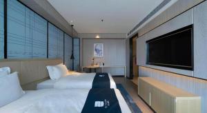 a bedroom with a large bed and a flat screen tv at Echarm Hotel Shenyang Nanta Shoe City Army General Hospital in Shenyang