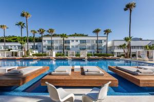 a swimming pool with lounge chairs and a building at So White Beach Resort in Ayia Napa