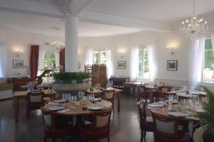 a dining room with tables and chairs and chandeliers at Hôtel Lac Et Forêt in Saint-André-les-Alpes
