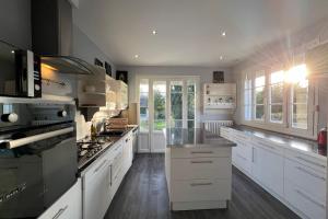 une grande cuisine blanche avec des armoires et des appareils blancs dans l'établissement Les Sablons, à La Houssaye-en-Brie