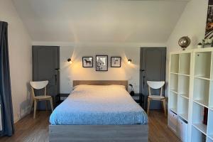 une chambre avec un grand lit et deux chaises dans l'établissement Les Sablons, à La Houssaye-en-Brie