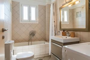 a bathroom with a tub and a sink and a toilet at Sun Blooming Villa In Tinos Island in Agios Romanos