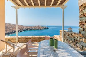 a table and chairs on a patio with a view of the ocean at Sun Blooming Villa In Tinos Island in Agios Romanos