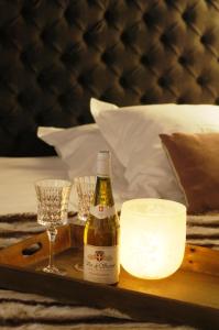 a tray with a bottle of wine and glasses on a bed at L'Epicerie Du Monal in Sainte-Foy-Tarentaise