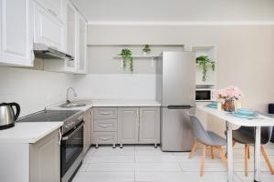 a white kitchen with a table and a refrigerator at Arbat Central Apartment in Almaty